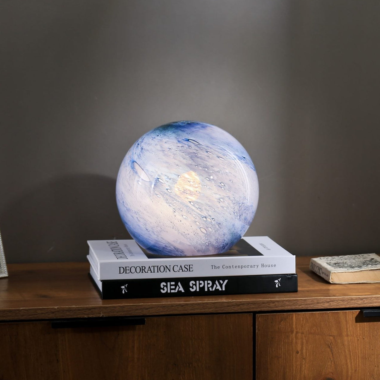Handblown glass globe lamp lit cool on a wooden side table